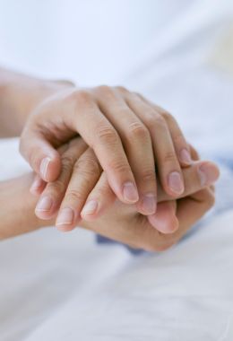 Two pairs of hands clasped together in a caring way.