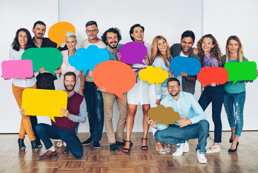 A group of men and women of diverse races each holding a speech bubble
